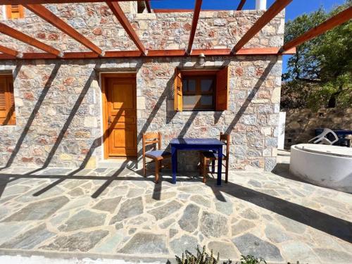 a stone house with a blue table and chairs on a patio at Beach Villa Lipsi Island Getaway in Lipsoi