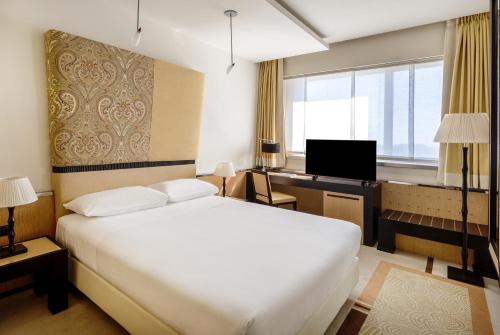 a bedroom with a white bed and a desk and a window at UNA Hotels Malpensa in Cerro Maggiore