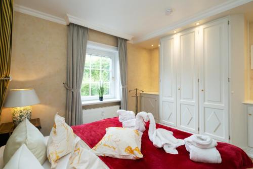 a bedroom with towels on a red bed at Hotel Parkresidenz Christian VIII in Archsum
