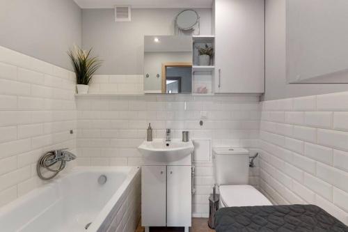 a white bathroom with a tub and a sink and a toilet at Motława 1 by Grand Apartments in Gdańsk