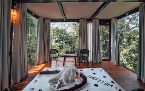 Habitación con cama y balcón con puertas correderas de cristal. en Arangala Forest Lodge, en Naula