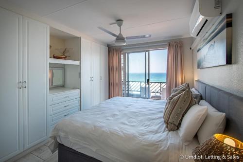 a bedroom with a bed and a view of the ocean at Isikulu 27B in Umdloti