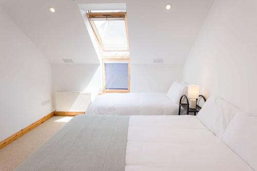a bedroom with two beds and a window at Kilkee Townhouse by Trident Holiday Homes in Kilkee