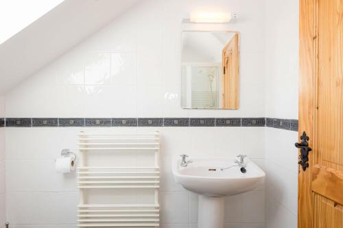 a white bathroom with a sink and a mirror at Kilkee Townhouse by Trident Holiday Homes in Kilkee