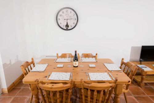 a large wooden table with chairs and a clock on the wall at Kilkee Townhouse by Trident Holiday Homes in Kilkee