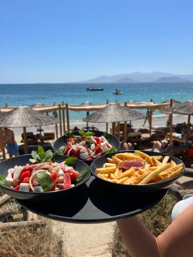 a table with three plates of food on the beach at Manios Suites in Agia Anna Naxos