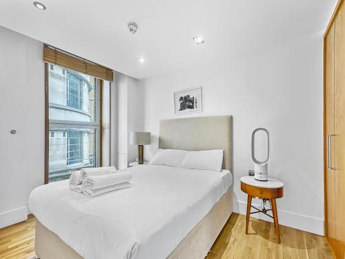 a white bedroom with a large bed and a window at Imperial Piccadilly Apartments in London