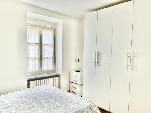 a white bedroom with a bed and white cabinets at ALLOGGIO MAIA in Biella