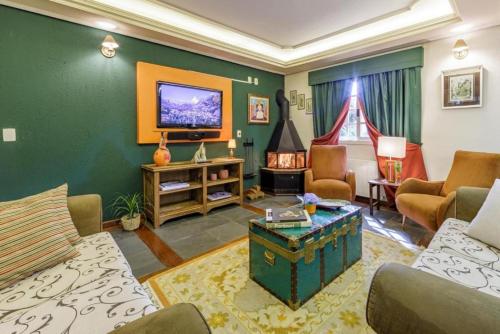 a living room with a couch and a tv at Tri Hotel Le Chateau in Gramado