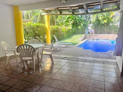 un patio con mesa, sillas y piscina en Casa Villas del Pacifico Puerto San José, en Puerto San José