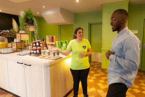 a man and a woman standing in front of a counter at ibis Besançon Centre la City in Besançon