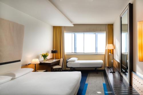 um quarto de hotel com duas camas e uma secretária em UNAHOTELS Malpensa em Cerro Maggiore