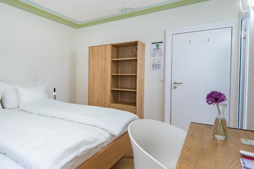 a bedroom with a bed and a desk with a vase of flowers at Linde Heiden Swiss Quality Hotel in Heiden