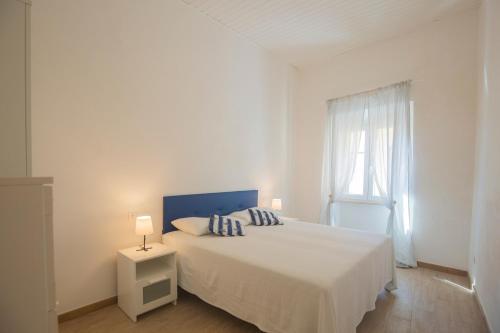 a white bedroom with a bed and a window at La Corte by HelloElba in Portoferraio