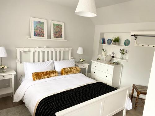 Dormitorio blanco con cama blanca y almohadas de oro en The Wren en Blackfordby