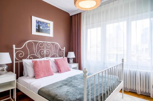 1 dormitorio con cama blanca y almohadas rojas en Spacious flat 5 min to Citys Nisantasi in Sisli, en Estambul