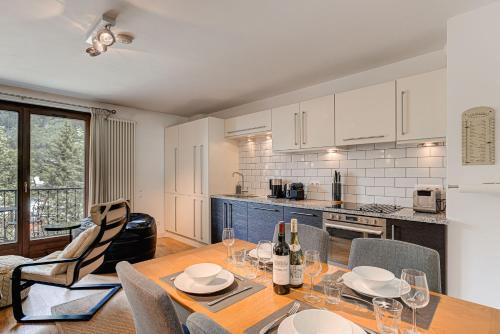 une cuisine avec une table et des chaises en bois ainsi qu'une cuisine avec des placards blancs dans l'établissement APARTMENT COSMIQUES - Alpes Travel - Central Chamonix - Sleeps 4, à Chamonix-Mont-Blanc