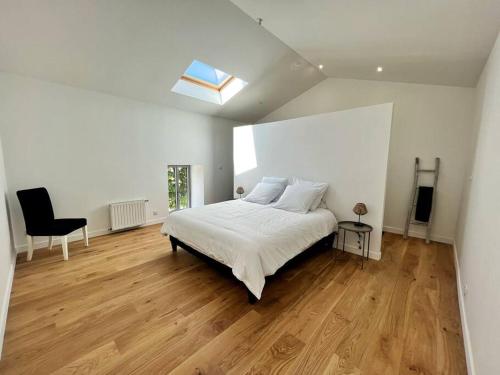 une chambre blanche avec un lit et une chaise dans l'établissement L'échappée - Villa avec piscine, à La Genilliere