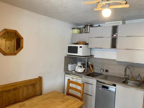 - une cuisine avec des appareils blancs et une table en bois dans l'établissement chaleureux T2 à MORILLON, à Morillon