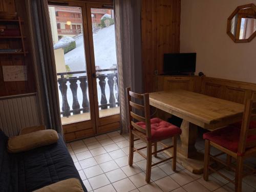 une salle à manger avec une table et des chaises et un balcon dans l'établissement chaleureux T2 à MORILLON, à Morillon