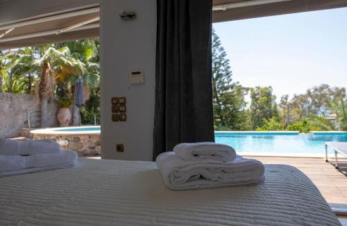 a bed with towels on it with a view of a pool at Green Villa Aegina in Aegenitissa