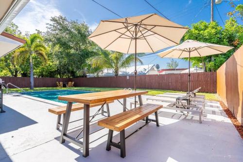 a table and benches with an umbrella and a pool at Bright 3 bedrooms Home Private Pool, 18 minutes to the Ocean in Hollywood