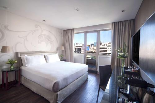 um quarto com uma cama branca e uma grande janela em NH Buenos Aires Tango em Buenos Aires