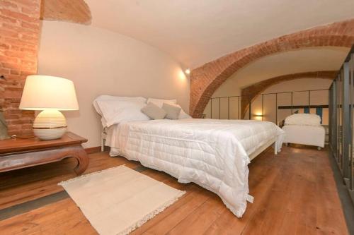 1 dormitorio con cama blanca y pared de ladrillo en Loft Principe Tommaso - San Salvario., en Turín