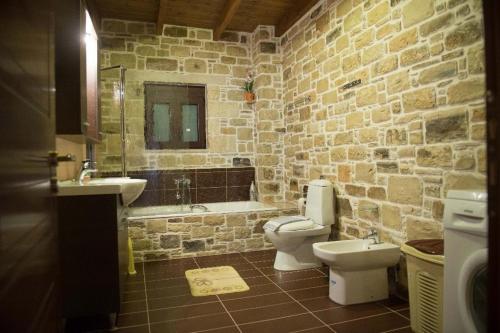 a stone bathroom with two toilets and a bath tub at Villas Alexandros Petrino in Kalamaki Heraklion