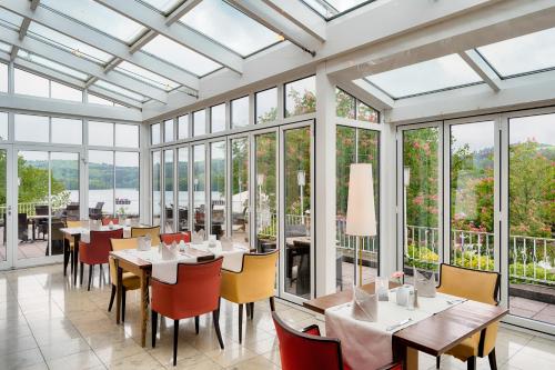 un comedor con mesas, sillas y ventanas en Welcome Hotel Meschede Hennesee, en Meschede