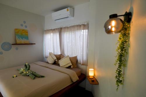 a bedroom with a bed and a window with a plant at Ocean Vibes in Thongsala