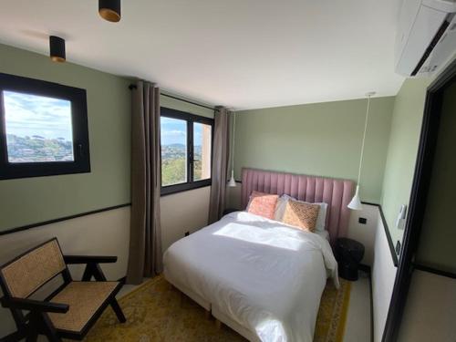 a bedroom with a bed and a chair and a window at Le Mazet des maisons du golf in Sainte-Maxime