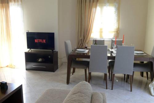 salon ze stołem, krzesłami i telewizorem w obiekcie SIMOS' sea view house w mieście Nikópolis