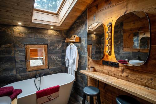 ein Badezimmer mit einer Badewanne, einem Waschbecken und einem Spiegel in der Unterkunft Savoya Lodges in Châtel