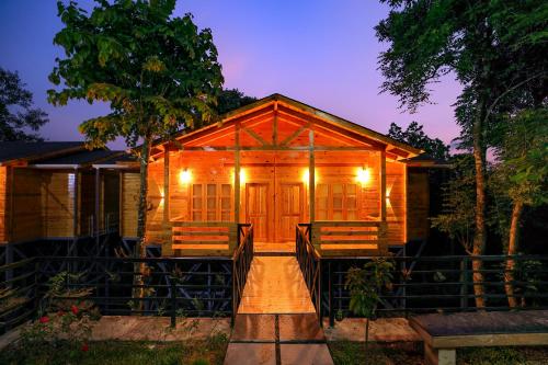 une cabane en bois avec terrasse couverte la nuit dans l'établissement Woodrose Resort, à Kalpatta