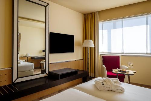 a hotel room with a mirror and a bed at UNA Hotels Malpensa in Cerro Maggiore