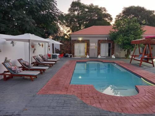 a swimming pool with lounge chairs and an umbrella at Eagles Nest Self-Catering Apartments in Gaborone