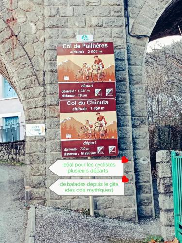 a sign with arrows on the side of a stone wall at les gites axéens (l'Ours) in Ax-les-Thermes