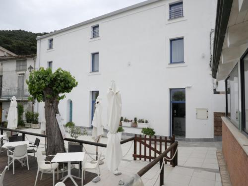 a balcony with tables and chairs and a white building at O Guarracino Rooms in Palinuro