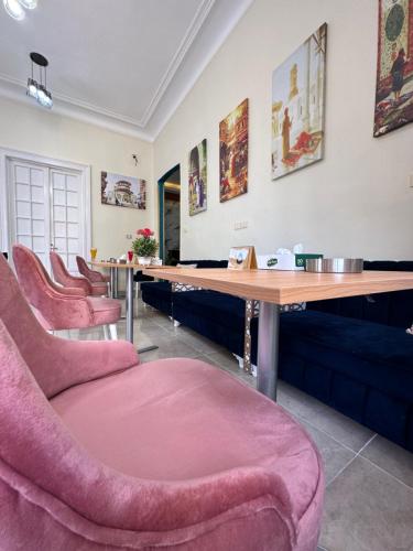 uma sala de espera com cadeiras cor-de-rosa e uma mesa de madeira em Victory Of Downtown Hotel no Cairo