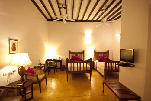 a living room with a couch and chairs and a tv at Maison Perumal Pondicherry - A CGH Earth Experience in Puducherry