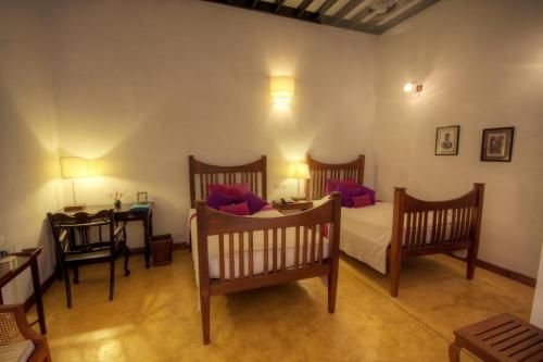 a bedroom with two beds and a table and a desk at Maison Perumal Pondicherry - A CGH Earth Experience in Puducherry