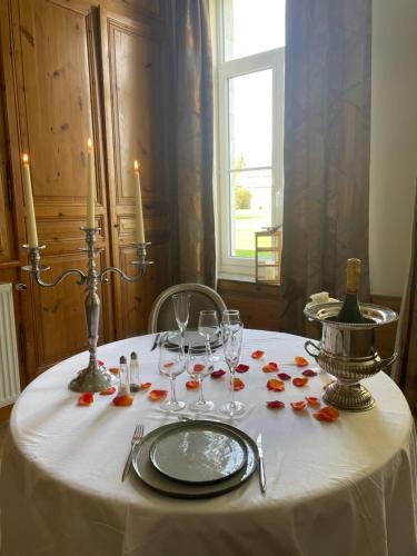 una mesa con mantel blanco con velas y copas de vino en Les Gîtes du Domaine de la Traxène, en Coupelle-Vieille
