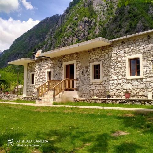 ein Steinhaus vor einem Berg in der Unterkunft Stomici Guesthouse in Ndërlysaj