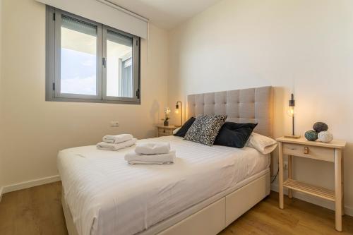 a bedroom with a large white bed with towels on it at Allo Apartments Bonald Piscina - Parking 3 Habitaciones in Jerez de la Frontera