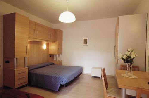 ein Schlafzimmer mit einem blauen Bett und einem Tisch und einem Schreibtisch in der Unterkunft Residence Helene in Tortoreto Lido
