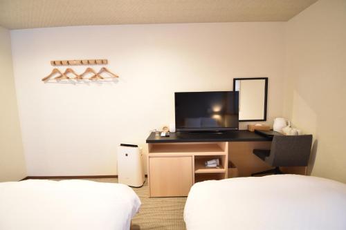 a room with two beds and a desk with a television at K-style 東本願寺 in Kyoto