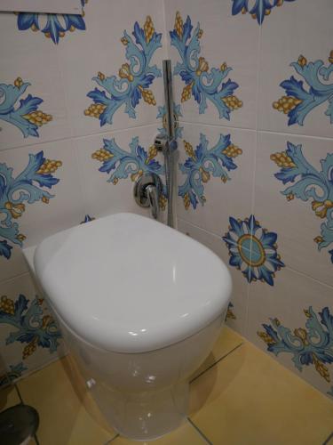 a toilet in a bathroom with blue and white tiles at O Guarracino Rooms in Palinuro