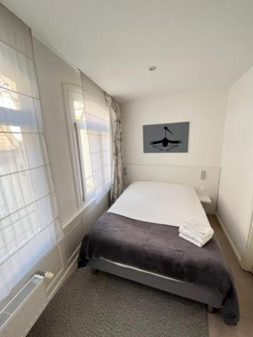 a small bedroom with a bed and two windows at Residence OLit Cathédrale in Strasbourg