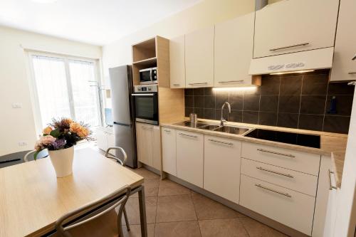 a kitchen with white cabinets and a table with flowers on it at Residenza IL CASTELLO in Sondrio